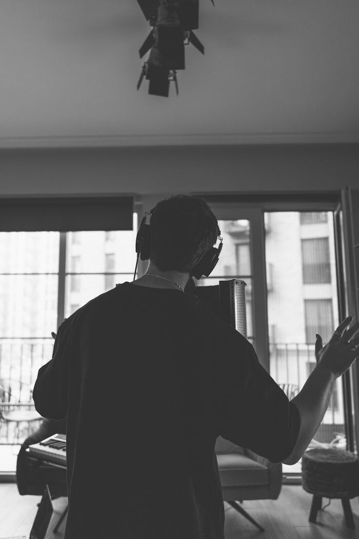 Black and white photo of a musician recording with headphones in a studio setting.