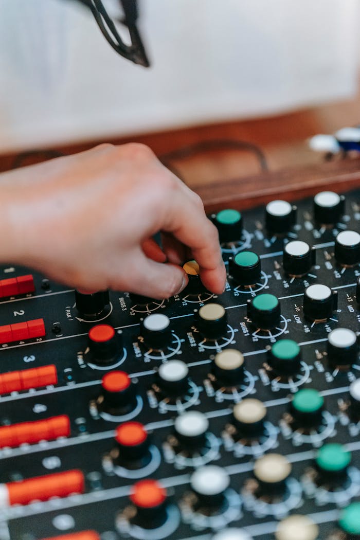 A hand adjusting controls on a professional audio mixing console, enhancing sound quality.